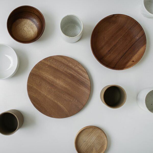 Flat lay of ceramic and wooden tableware on a white surface, showcasing minimalism and elegance.